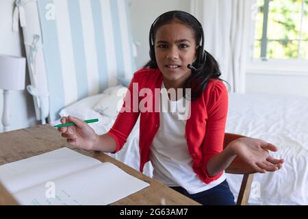 Ragazza afroamericana che ha una lezione di videochiamata indossando le cuffie a casa Foto Stock