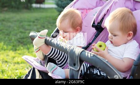 Gemelli in un carrello del bambino sul camminare con le mele. Foto Stock