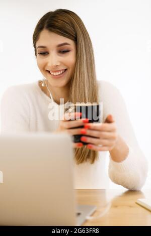Bella donna caucasica che pensa a qualcosa mentre si siede con un notebook in un bar caffè minimale. Affascinante freelance femminile che pensa a nuove idee durante il lavoro sul computer portatile bere caffè Foto Stock