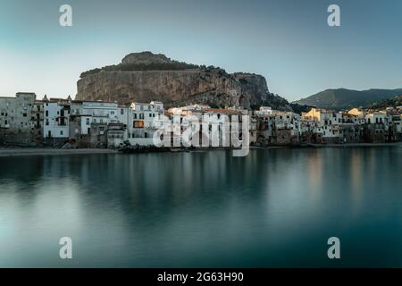 Alba nel porto di Cefalù, Sicilia, Italia, vista panoramica della città vecchia con colorate case lungomare, mare e la Rocca Cliff.Attractive estate Foto Stock