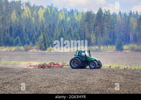 Campo coltivatore con trattore verde Deutz-Fahr Agrotron 135 e erstad NZ con erpice a denti aggressivo in primavera. Salo, Finlandia. 13 maggio 2021 Foto Stock