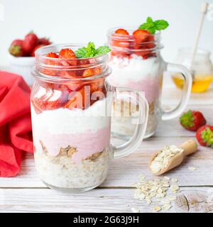 Una proposta di una sana colazione preparata a casa. Farinata d'avena con muesli, yogurt greco e fragole. Foto Stock