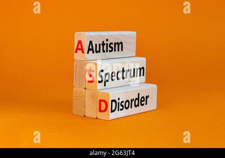 ASD, simbolo di disturbo dello spettro autistico. Blocchi di legno con parole 'ASD, disturbo dello spettro autistico'. Sfondo arancione. Medico e ASD, spettro autismo di Foto Stock