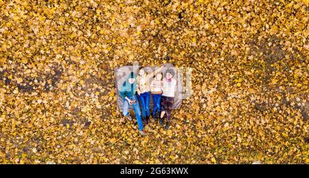 Vista dall'alto sulla famiglia adagiata su foglie gialle Foto Stock