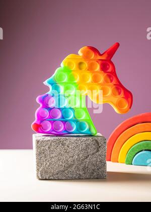 Pop esso giocattolo, colori arcobaleno, in forma di unicorno. Giocattolo anti-stress multicolore, sensoriale fidget pop it . Messa a fuoco selettiva Foto Stock