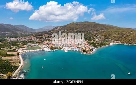 Antica spiaggia di Epidauro e porto turistico nel Peloponneso. Vista panoramica aerea e drone delle barche tradizionali del villaggio e delle navi ormeggiate al porto di Argolida Foto Stock