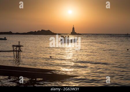 Ahtopol - 10 settembre: Sagoma di una barca con i pescatori di ritorno dalla pesca tra rocce e faro all'alba il 10 settembre 2016, Ahtopol Foto Stock