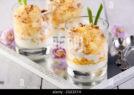 Insalata di pollo con ananas, mais, condita con yogurt greco, noci tritate e formaggio grattugiato. Un'insalata in un bicchiere, un'ottima idea per servire il cibo in p Foto Stock