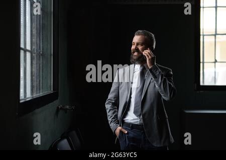 Ritratto di uomo d'affari maturo in piedi in interni, utilizzando smartphone. Foto Stock