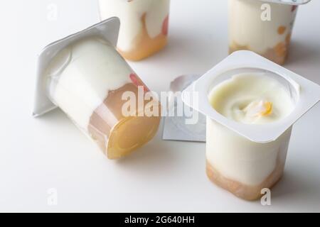 Tazze di yogurt cremoso naturale con gelatina di confettura di mirtilli pronti da mangiare - isolate su bianco con spazio per la copia Foto Stock