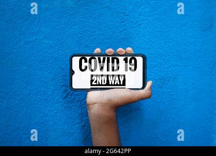 Covid 19 2 ° modo formulazione sullo schermo dello smartphone isolare su sfondo blu con copyspace per il testo. Foto Stock