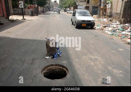 I pendolari attraversano una vicina rete fognaria aperta che può causare incidenti specialmente nelle ore notturne, mostrando la negligenza dei dipartimenti interessati, a Risala Road a Hyderabad venerdì 02 luglio 2021. Foto Stock