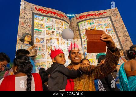 KOLKATA, INDIA - 9 FEBBRAIO 2018 : Padre che prende selfie con bambino alla fiera del libro di Kolkata di notte. E' il più grande, frequentato e famoso del mondo Foto Stock