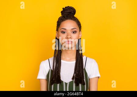 Foto di grave giovane pelle scura donna calma viso pacifico Dreadlocks capelli isolati su sfondo giallo Foto Stock