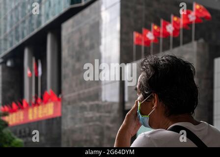 Hong Kong, Cina. 01 luglio 2021. Un uomo riposa come Repubblica popolare Cinese e le bandiere della RAS di Hong Kong sono viste sullo sfondo a Hong Kong il 1° luglio 2021. Hong Kong celebra il suo 24° anniversario della consegna in Cina e il 100° anniversario della fondazione del Partito comunista cinese. Credit: SOPA Images Limited/Alamy Live News Foto Stock