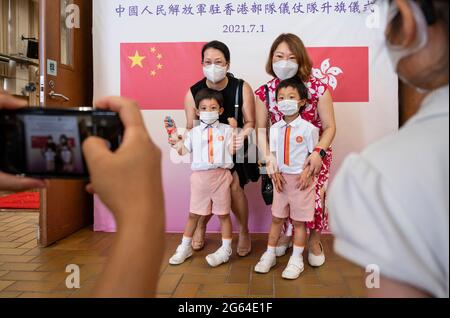 Hong Kong, Cina. 01 luglio 2021. Le famiglie posano per una fotografia di fronte a un cartellone che mostra le bandiere cinesi e della RAS di Hong Kong mentre prendono parte alla cerimonia di innalzamento della bandiera alla scuola media di Pui Kiu a Hong Kong il 1 luglio 2021. Hong Kong celebra il suo 24° anniversario della consegna in Cina e il 100° anniversario della fondazione del Partito comunista cinese. Credit: SOPA Images Limited/Alamy Live News Foto Stock
