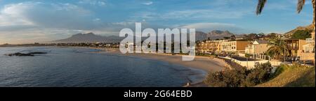 GORDONS BAY, SUDAFRICA - 12 APRILE 2021: Vista panoramica del tramonto sulla spiaggia di Gordons Bay nella provincia del Capo Occidentale. Persone ed edifici sono v Foto Stock