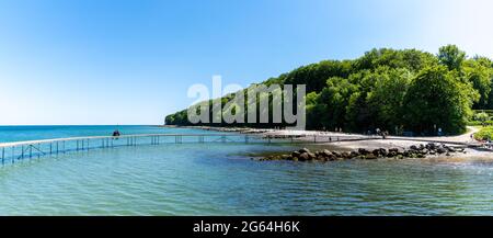 Panorama della gente alla baia di Aarhus con il Ponte Infinito in primo piano e la foresta dietro sotto un cielo blu senza nuvole Foto Stock