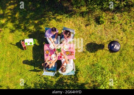 Vista dall'alto gli amici che trascorrono del tempo libero in giardino cucinando barbecue bevendo birra al tavolo Foto Stock