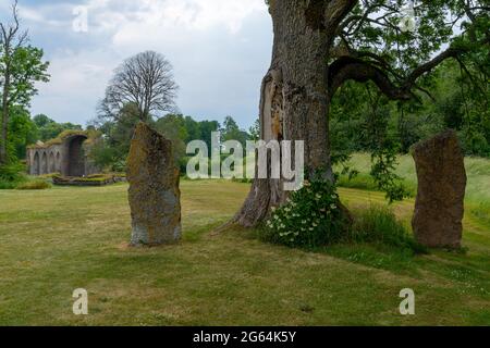 Alvastra, Svezia - 20 giugno 2021: Grandi massi obelischi con le rovine dell'abbazia di Alvastra sullo sfondo Foto Stock