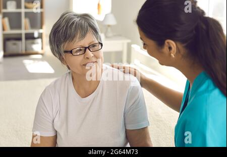 Ritratto dell'infermiere femminile che mette la mano sulla spalla della paziente della donna anziana Foto Stock