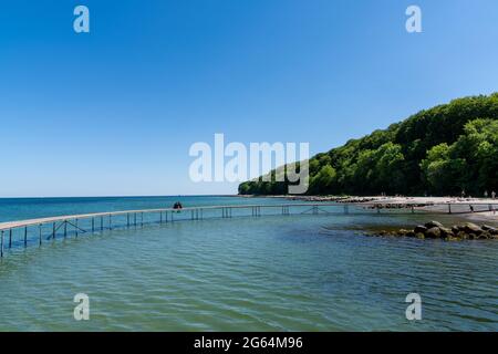 La gente alla baia di Aarhus con il Ponte Infinito in primo piano e la foresta dietro sotto un cielo blu senza nuvole Foto Stock