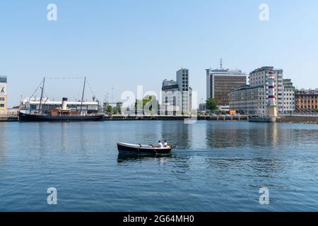 Malmo, Svezia - 18 giugno 2021: Piccola barca che attraversa il porto con il centro di Malmo e il faro sullo sfondo Foto Stock
