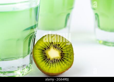 Dolce dessert, gelatina di kiwi in bicchieri di vetro e accanto al kiwi fresco, tagliato in due metà su uno sfondo bianco Foto Stock