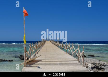 Bandiera rossa sul lungo molo in giornata di sole Foto Stock