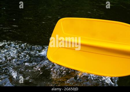 La pagaia in kayak tocca l'acqua e crea schizzi e increspature sull'acqua Foto Stock