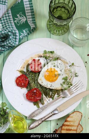 Uova fritte con fagioli verdi, pomodori con vino bianco su fondo verde di legno Foto Stock