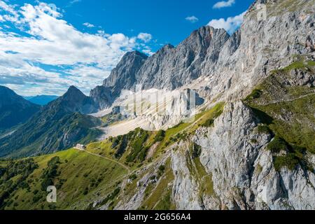 Vista sul massiccio di Sudwand Hutte e Hoher Dachstein in una giornata estiva soleggiata da una funivia. Ripide scogliere rocciose e una vasta valle alpina sottostante in Austria Foto Stock