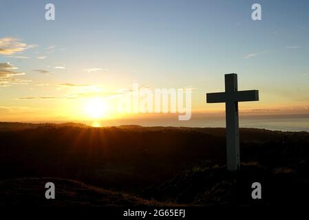 A Cross si trova sulla collina all'ora del tramonto Foto Stock