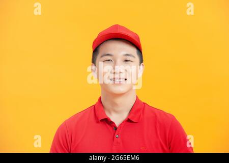 felice lavoratore deliveryman indossando il cappuccio e uniforme guardando la macchina fotografica Foto Stock