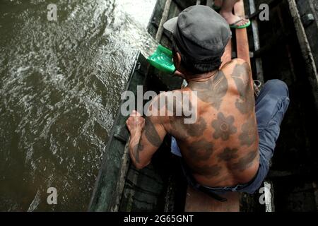 Ramping, membro della tradizionale comunità Dayak IBAN a Sungai Utik, Kalimantan occidentale, Indonesia. Anziano con molti tatuaggi tradizionali sul suo corpo, il signor Ramping era una delle persone più antiche della comunità, che ricopriva un ruolo importante nei rituali e nelle tradizioni. In questa foto d'archivio, stava aiutando togliendo l'acqua dalla barca durante un viaggio ecoturismo. Foto Stock