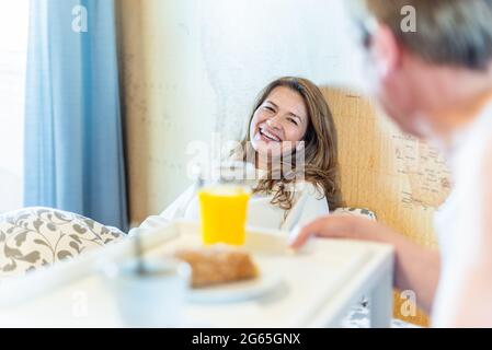 Uomo maturo innamorato portando la sua moglie prima colazione a letto su un vassoio Foto Stock