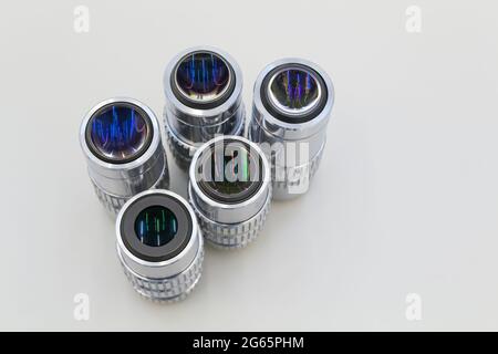 Molti obiettivi sono diversi dall'ingrandimento su sfondo bianco. Primo piano degli obiettivi del microscopio. Foto Stock