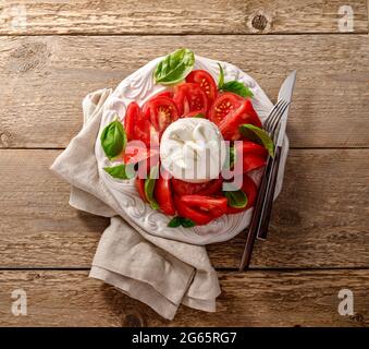 Insalata burrata su piatto bianco vintage. Vista dall'alto dell'insalata con burrata e foglie di basilico. Foto Stock