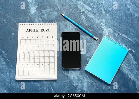 Calendario cartaceo, cancelleria e telefono cellulare su sfondo a colori Foto Stock