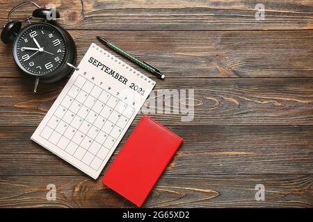 Calendario in carta, sveglia e notebook su sfondo in legno Foto Stock