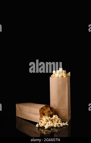Sacchetti di carta con gustosi popcorn su sfondo scuro Foto Stock