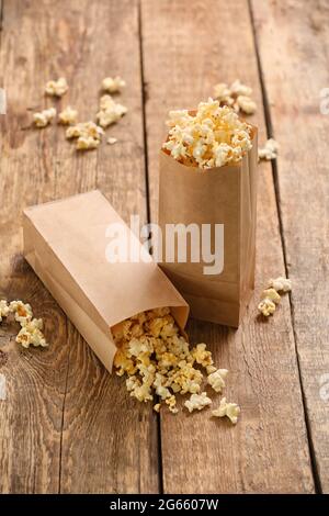 Sacchetti di carta con gustosi popcorn su sfondo di legno Foto Stock