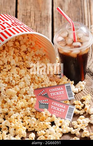 Secchio con gustosi popcorn, biglietti per il cinema e cola su sfondo di legno, primo piano Foto Stock