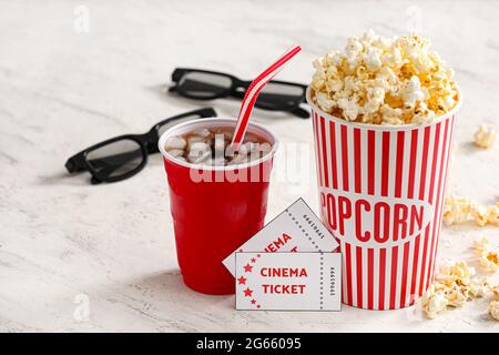 Gustosi popcorn con Cola e biglietti per il cinema su sfondo chiaro, primo piano Foto Stock