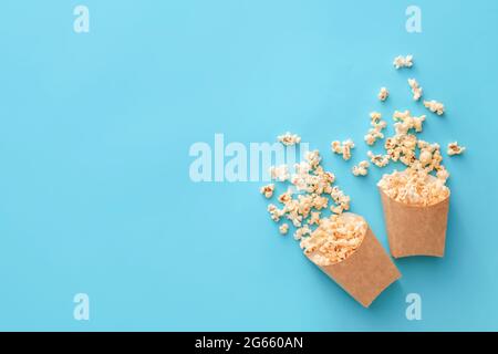 Sacchetti di carta con gustosi popcorn su sfondo a colori Foto Stock