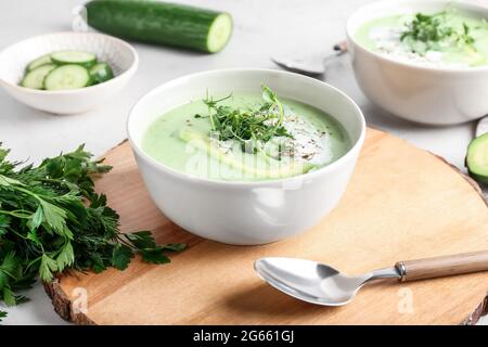 Ciotole con gazpacho verde e ingredienti su sfondo chiaro Foto Stock