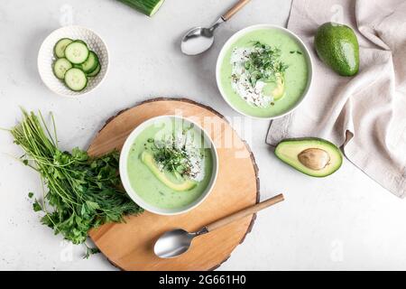 Ciotole con gazpacho verde e ingredienti su sfondo chiaro Foto Stock