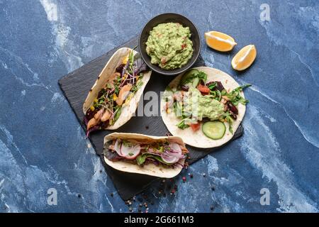 Sali a bordo con tacos e gustosa guacamole in ciotola su sfondo colorato Foto Stock