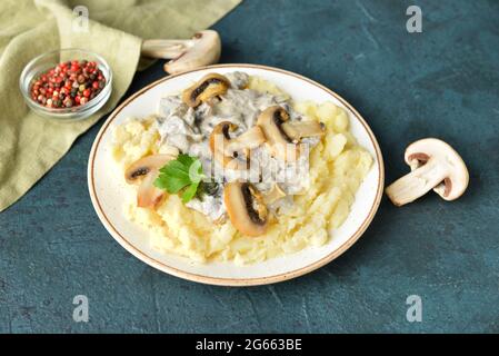 Piatto con gustosi purè di patate, funghi e peppercorn su sfondo colorato Foto Stock