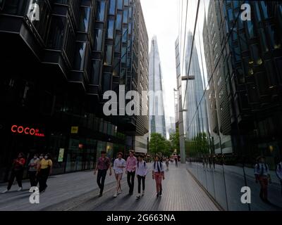 Londra, Greater London, England - Giugno 26 2021: Gli adolescenti alla moda camminano lungo più London Riverside. Il grattacielo Shard si riflette negli edifici. Foto Stock